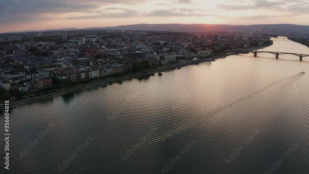 Establishing Mainz and its Dom church by a drone on a sunny summer night in old Germany with the flate rine River and a lonely boat in the background Establishing Mainz and its Dom church by a drone on a sunny summer night in old Germany with the flate rine River and a lonely boat in the background