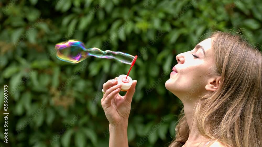 Attractive woman on a summer day in the park is playing by blowing soap bubbles. Attractive woman on a summer day in the park is playing by blowing soap bubbles.