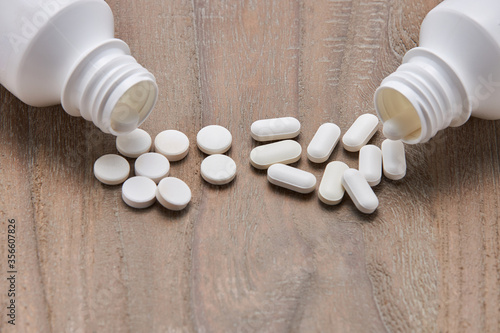 Bottle colorful tablets and capsules on wooden background. Health care concept