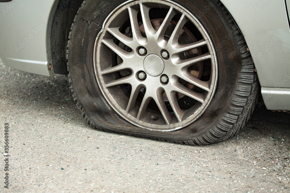 Flat car tyre and damaged wheel rim. Close-up side view.