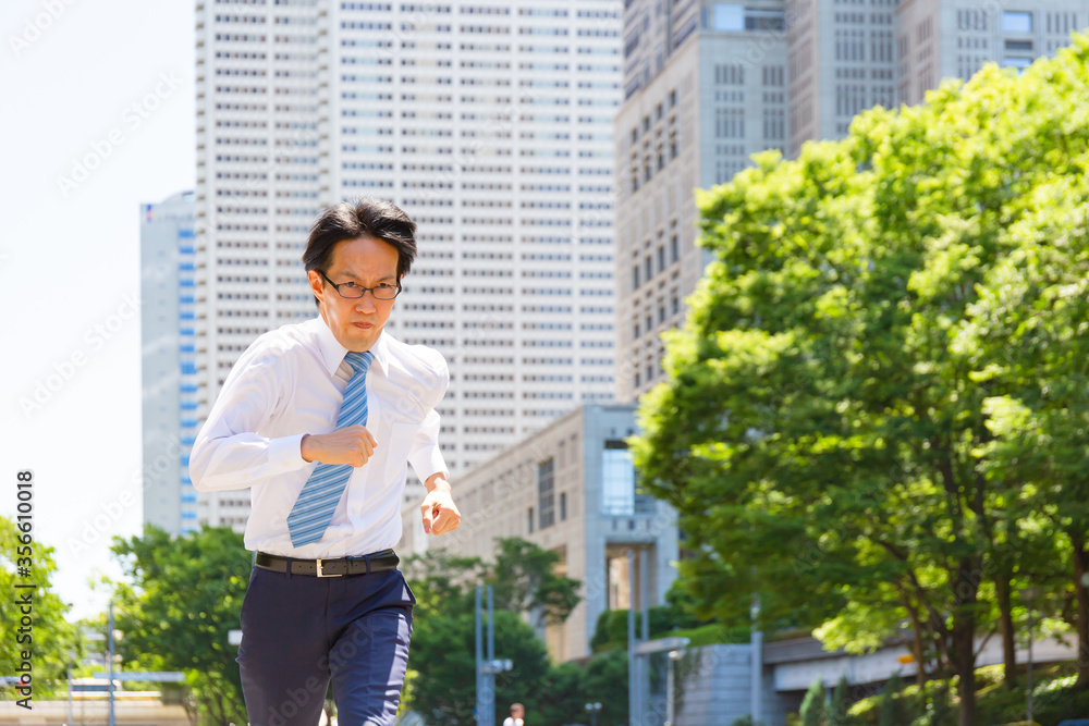 やせ型の真面目そうな日本人ビジネスマンが真剣に走っている
