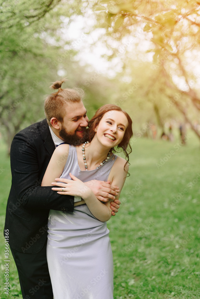 a young beautiful couple, a girl in a lilac dress and a man in black in a summer Park with Apple trees