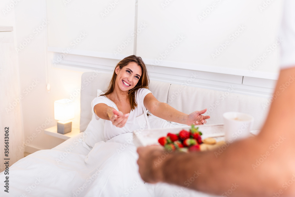 Care and romance at the morning. Surprised and happy young woman lying at the bed with male hands bringing breakfast. Good morning! Healthy breakfast in bed. Care and romance at the morning. Surprised and happy young woman lying at the bed with male hands bringing breakfast. Good morning! Healthy breakfast in bed.