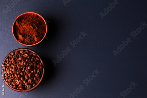 Roasted and ground beans in clay bowls dark blue table background. Close-up, top view, copy space. Coffee shop, morning, baristas workplace concept