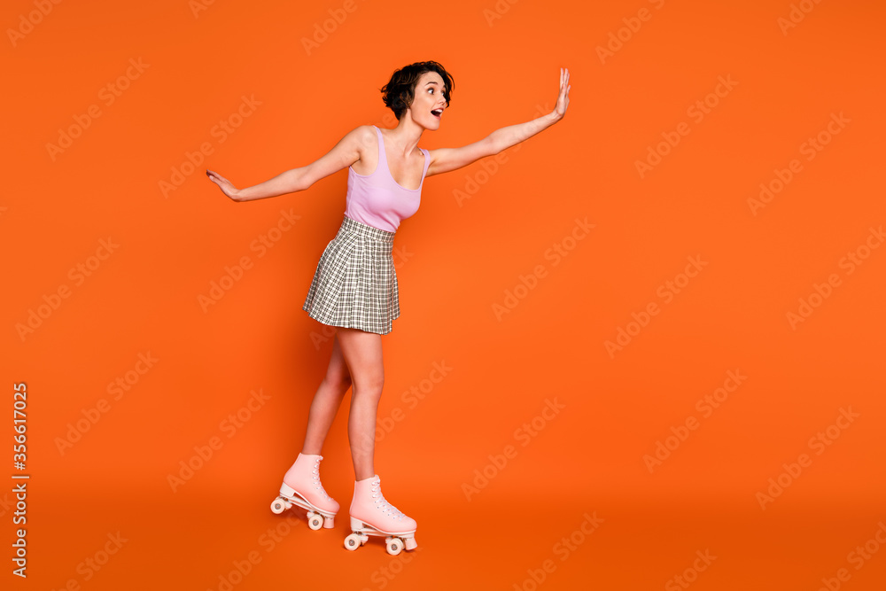 Full size profile side photo of positive cheerful girl ride skates copyspace impressed hold hand wear good look clothes isolated over bright color background Full size profile side photo of positive cheerful girl ride skates copyspace impressed hold hand wear good look clothes isolated over bright color background