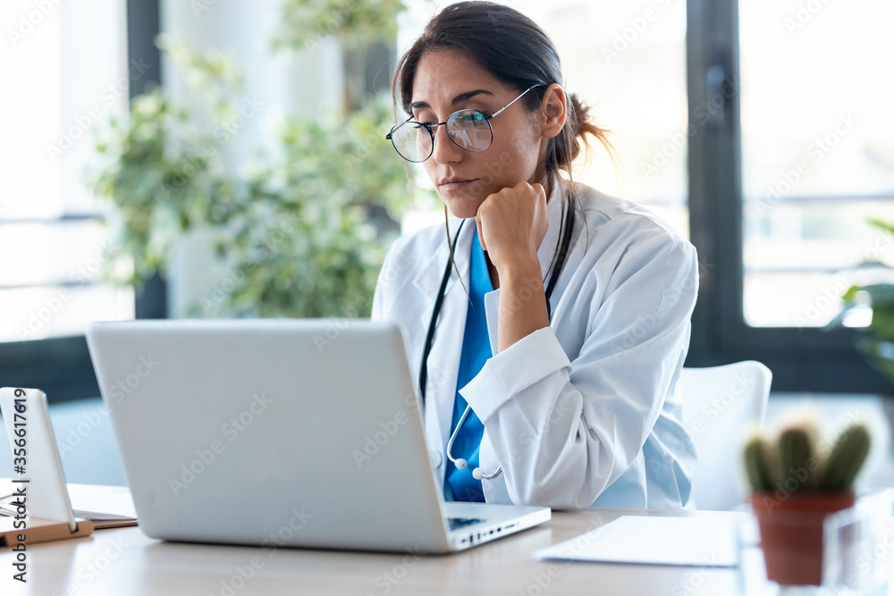 Serious female doctor working with her laptop in the consultation. Serious female doctor working with her laptop in the consultation.