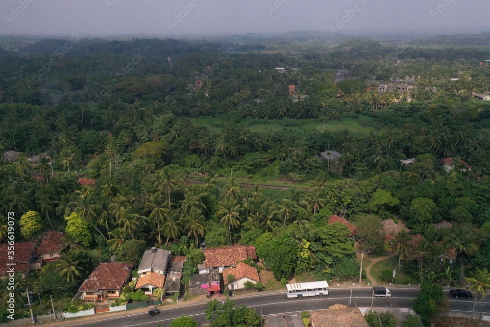 natural aerial drone bird view day shot of the sea shore with a road, beautiful villas and green forest trees. Pitiwella, Sri Lanka