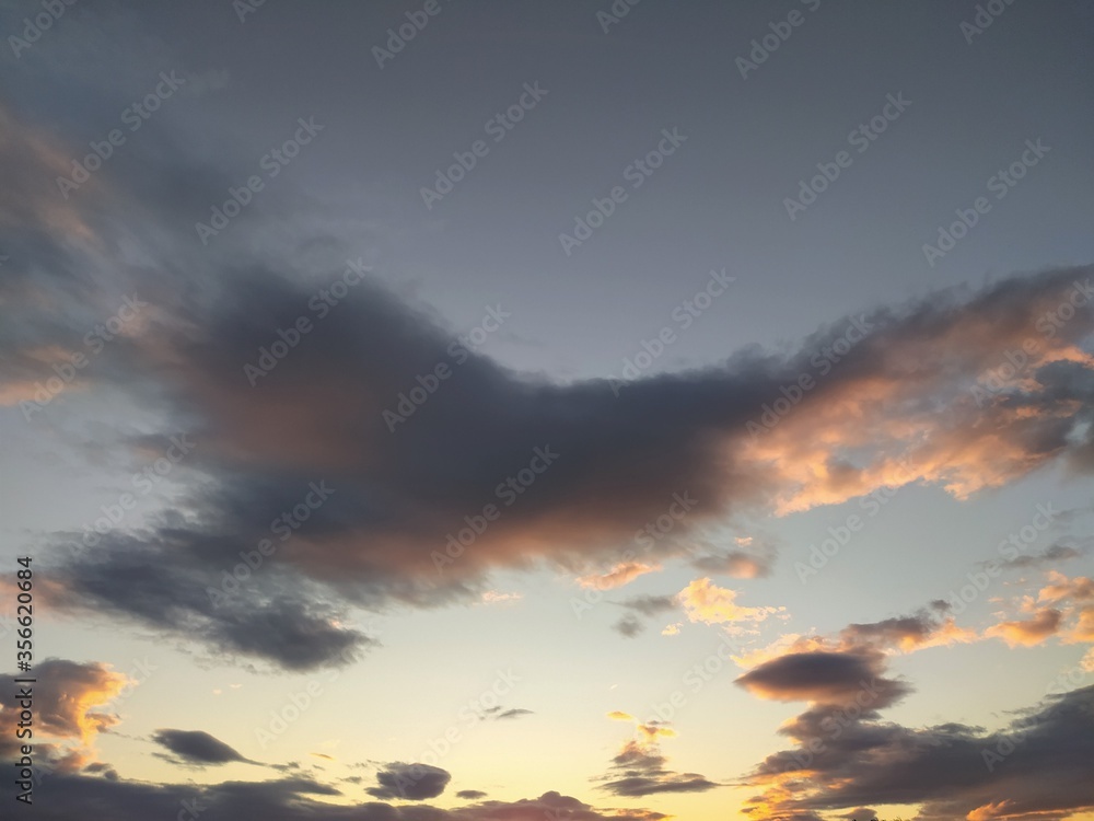 Sunset in the clouds, background. Beautiful sky with gray and gold clouds , unstable changeable weather. 