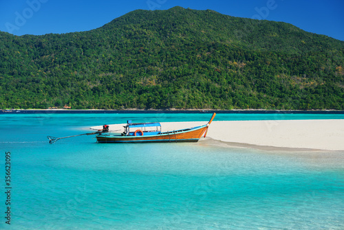 Boat on tropical sea coast with white sandy beach and turquoise water
