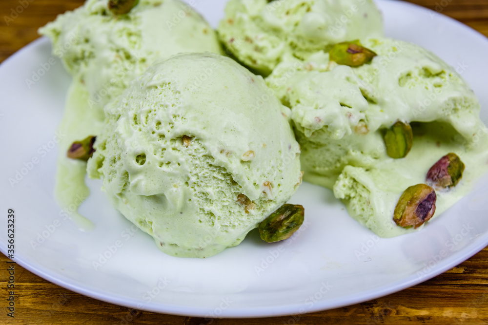 Glass bowl with pistachio ice cream balls and nuts on a wooden table Glass bowl with pistachio ice cream balls and nuts on a wooden table