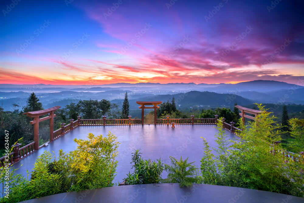 Fototapeta premium Dawn in front of temple gate with impressive colorful clouds in sky shines under mist valley to attract tourists to relax, meditate near Da Lat , Vietnam