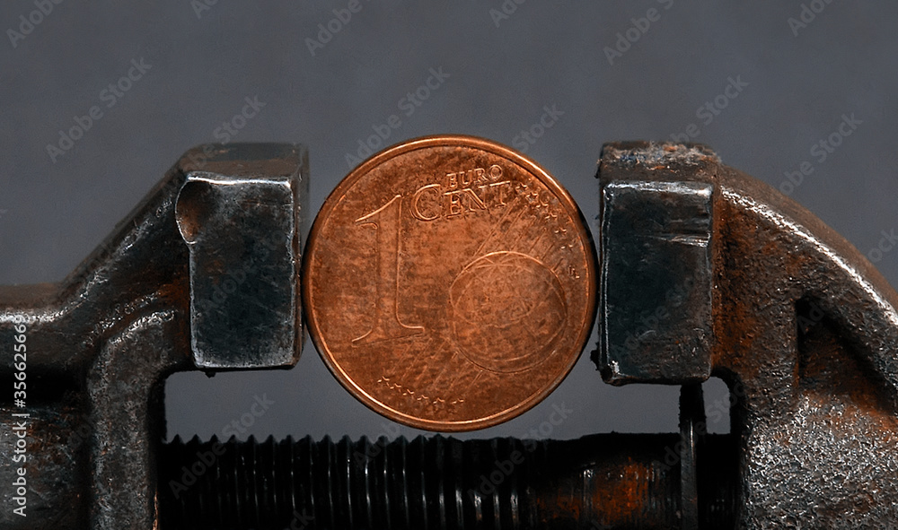 One cent euro coin, clamped in a metal vice. Concept One cent euro coin, clamped in a metal vice. Concept