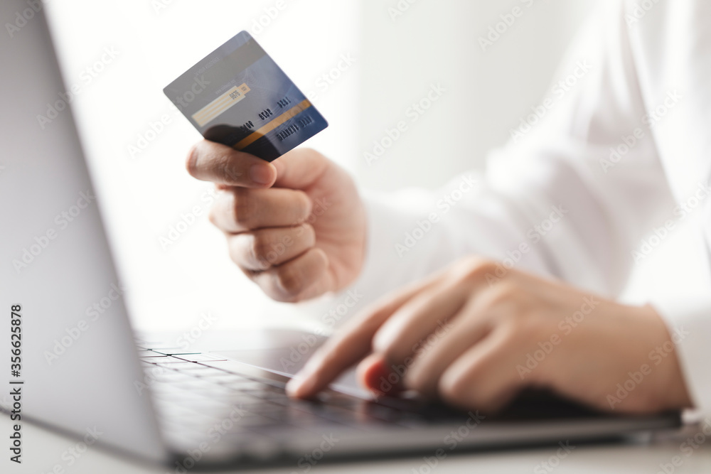 Hands holding credit card and using laptop computer, Businesswoman working at home, Online shopping, E-commerce, Spending money, Internet banking. Hands holding credit card and using laptop computer, Businesswoman working at home, Online shopping, E-commerce, Spending money, Internet banking.