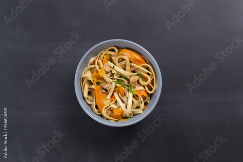 Udon noodles with chicken on a black background. Top view. Minimalism. Japanese cuisine.
