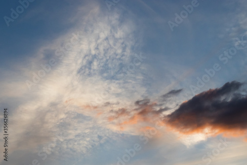 Light and dark clouds at sunset with blue sky background