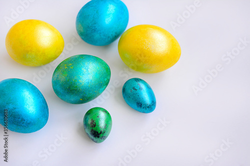 Close-up of colored eggs of yellow, blue and green color on a white background. Easter. Top view