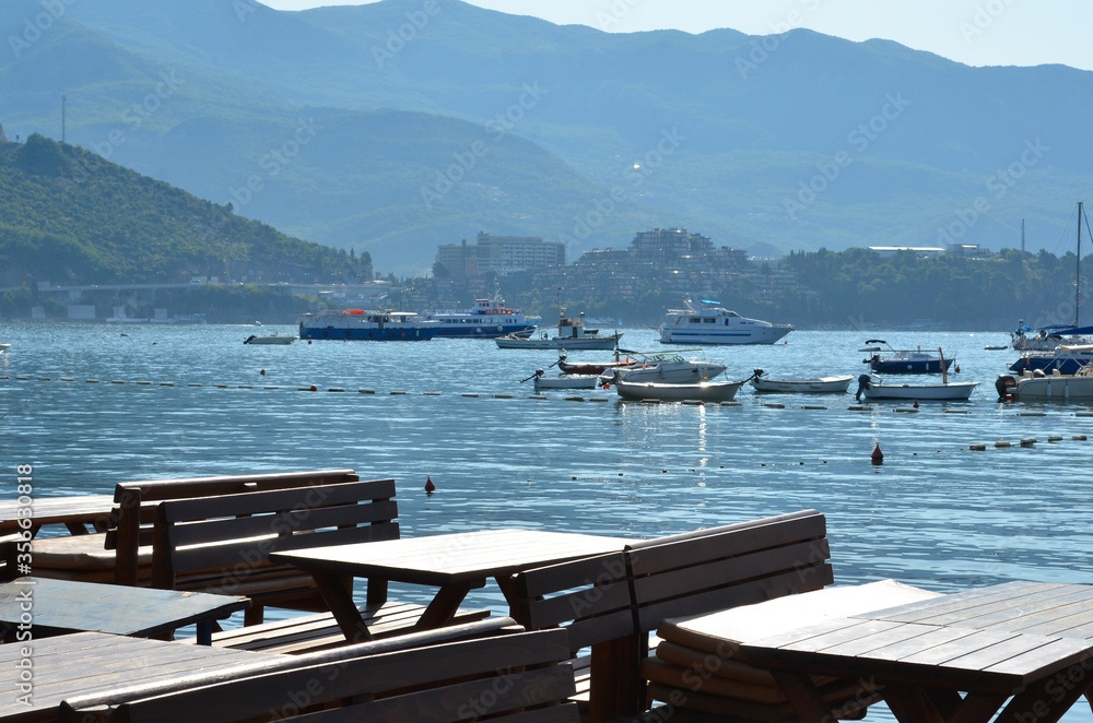 Restaurant by the sea, boats and mountains in the background