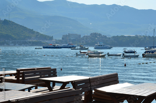 Restaurant by the sea, boats and mountains in the background