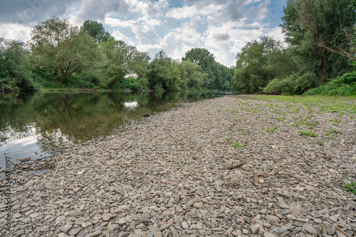 Flat gravel bank on a small river on a cloudy day. Downstream