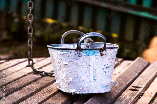 White bucket on weathered wooden planks, rustic well in the countryside photo