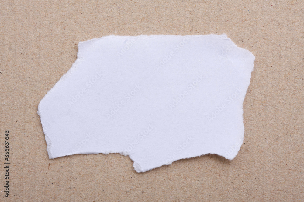 Obraz premium A torn piece of White Paper a brown paper cardboard. Copy Space. 