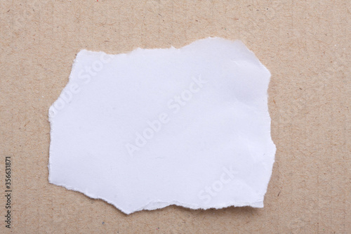 A torn piece of White Paper a brown paper cardboard. Copy Space. 