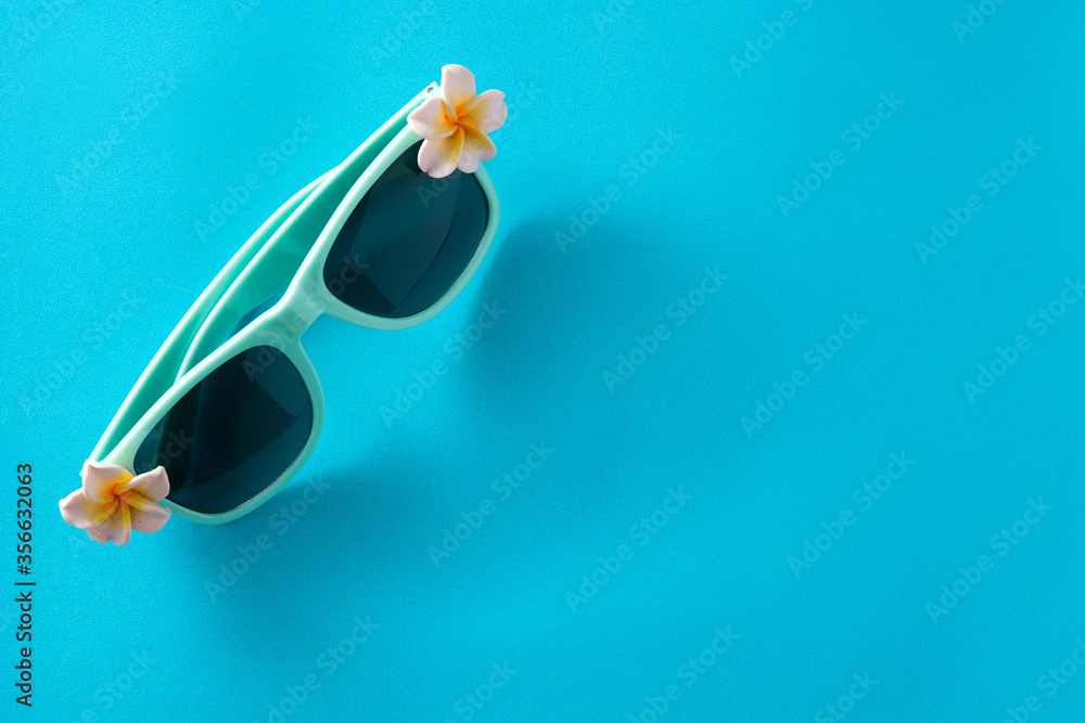 Sunglasses with flowers on blue background. Copy space Sunglasses with flowers on blue background. Copy space