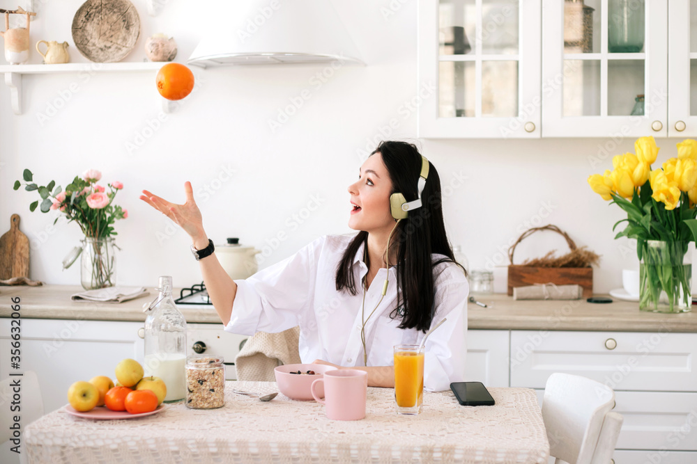 Young beautiful woman enjoying music and coffee while breakfast in kitchen.