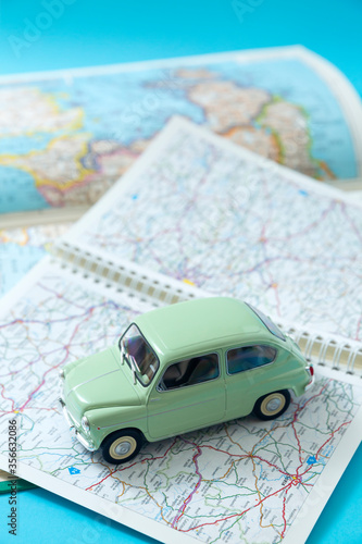 European classic car in miniature driving through a road map. Space for text. Concept of travel and tourism by car.