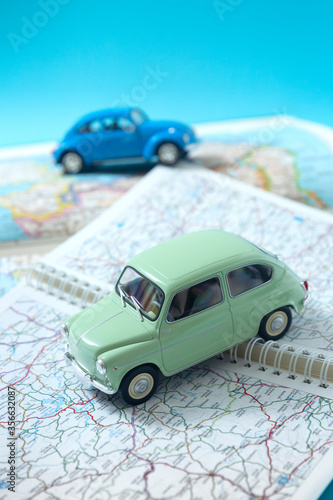 Two miniature classic cars driving through a road map. Space for text. Concept of travel and tourism by car.