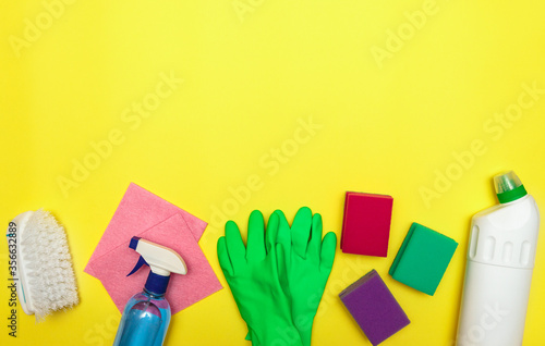 Set of cleaning and detergents, gloves and a brush on a yellow background, space for text. Cleaning. Disinfection. Flat lay.