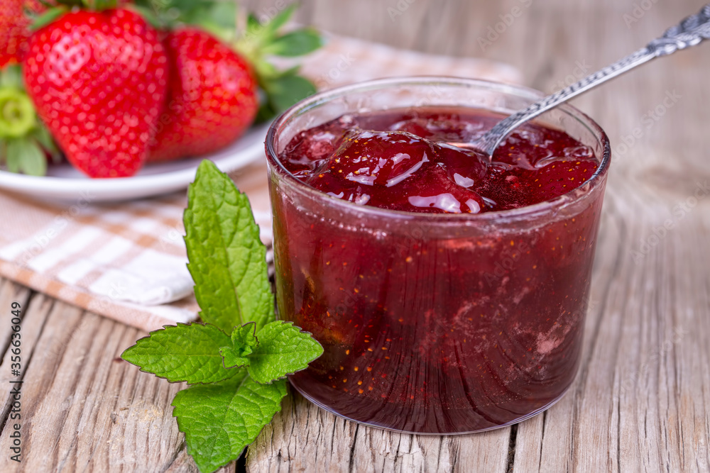 Homemade delicious strawberry jam and strawberry on a rustic wooden table Homemade delicious strawberry jam and strawberry on a rustic wooden table