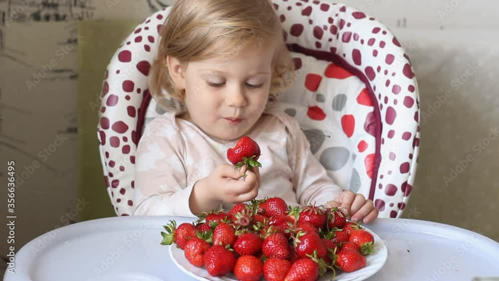 A child girl eats strawberries. Close-up A child girl eats strawberries. Close-up