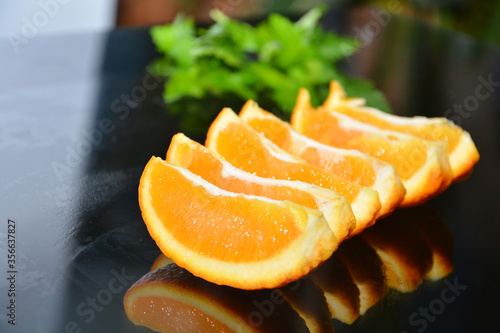 fresh  cutted orange with the green parsley  on the black glass