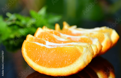 fresh  cutted orange with the green parsley  on the black glass