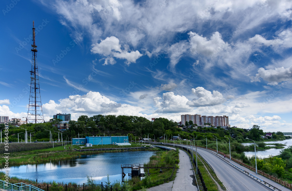 Panoramic view to Irkutsk city, small pond with reflection, TV tower and road from the academic bridge in sunny summer day with beautiful clouds