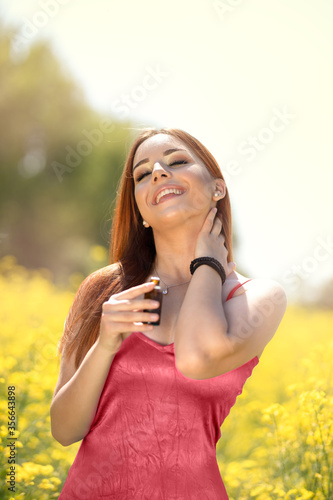 Smiling woman applying cosmetic oil. Perfume, cosmetics concept.