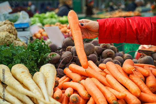 Sales of fresh and organic fruits and vegetables at the green market or farmers market. Citizens buyers choose and buy products for healthy food. female choosing the best carrot. lifestyle.