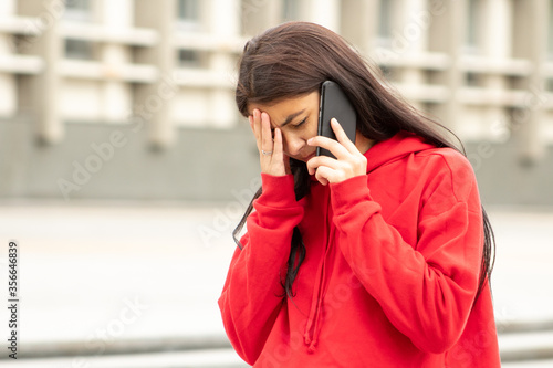 Fotografie Worried dark woman heard bad from her boyfriend on the phone on the street