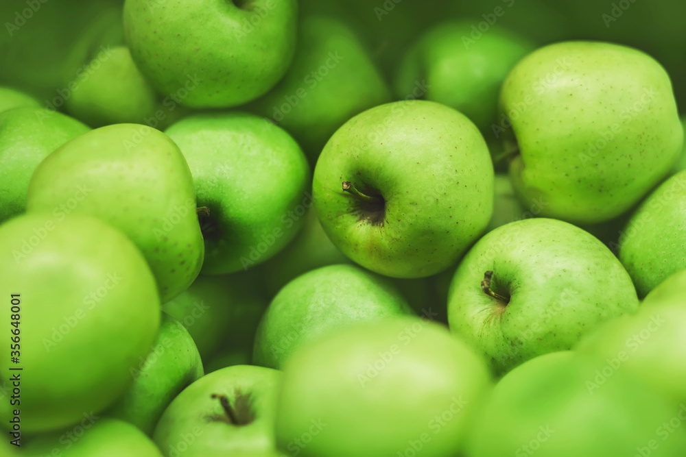 Green ripe sweet delicious apples are lying in a pile in the grocery store. Vegetarianism. Fruit.