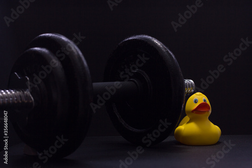 Black metal dumbbell for fitness with a duck, on a black background.