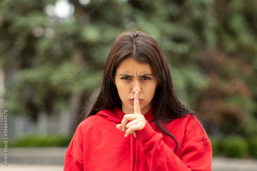 An indignant beautiful dark-skinned woman in red shows that her colleagues need to be quieter on the street An indignant beautiful dark-skinned woman in red shows that her colleagues need to be quieter on the street