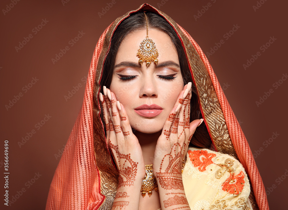 Mehndi. Portrait of beautiful indian girl in saree. Young hindu woman model with kundan golden jewelry set. Traditional Indian costume lehenga choli. Henna art mehendi on woman's hands.
