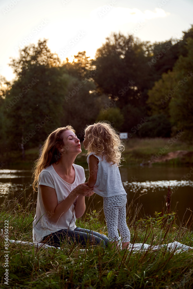 Fototapeta premium Mom and daughter on the street are looking at each other. Laughter and joy of a woman and a child. High quality photo