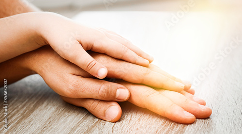 Happy family holding hands at wooden table indoors  closeup. Banner design