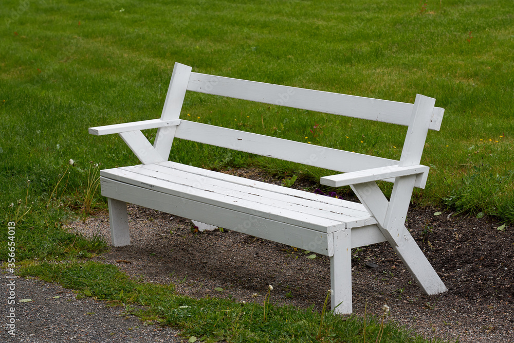 A wooden bench in a park with green grass on a background. A wooden bench in a park with green grass on a background.
