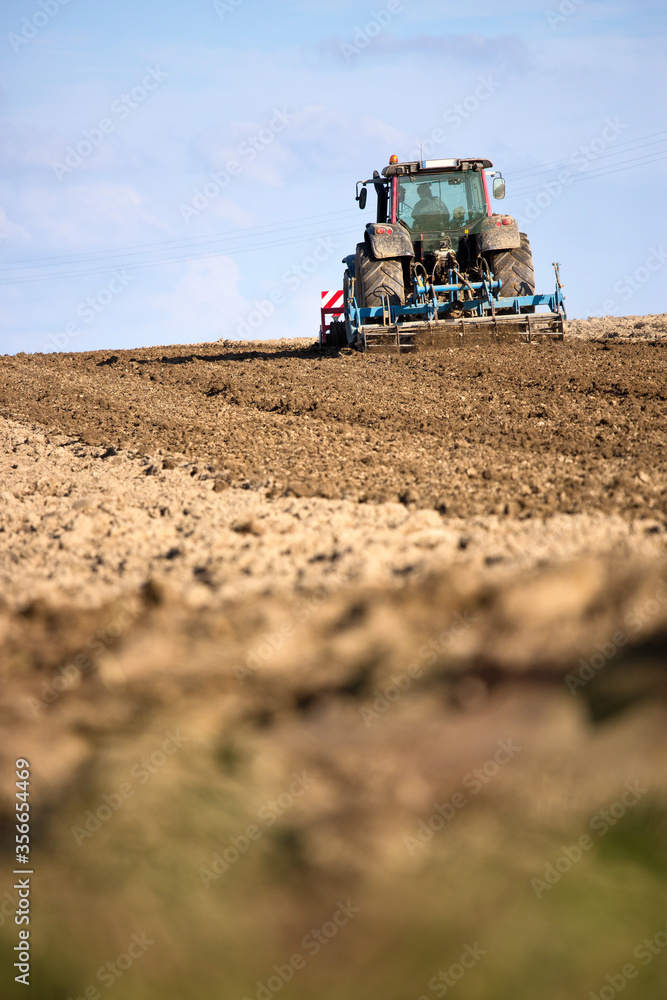 Fototapeta premium Tracteur travaillant la terre au champ, paysage de campagne.