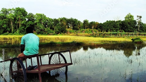 A farmer seating in a wetland over a thela (Carrier)