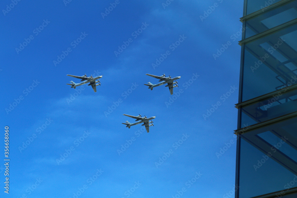 a triangular formation of a group of three russian military fighter jet planes flying high in blue sky during Vicotry Day parade air show on 9 May in Moscow, Russia a triangular formation of a group of three russian military fighter jet planes flying high in blue sky during Vicotry Day parade air show on 9 May in Moscow, Russia