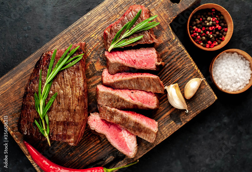  Two grilled beef steaks with spices on a stone background